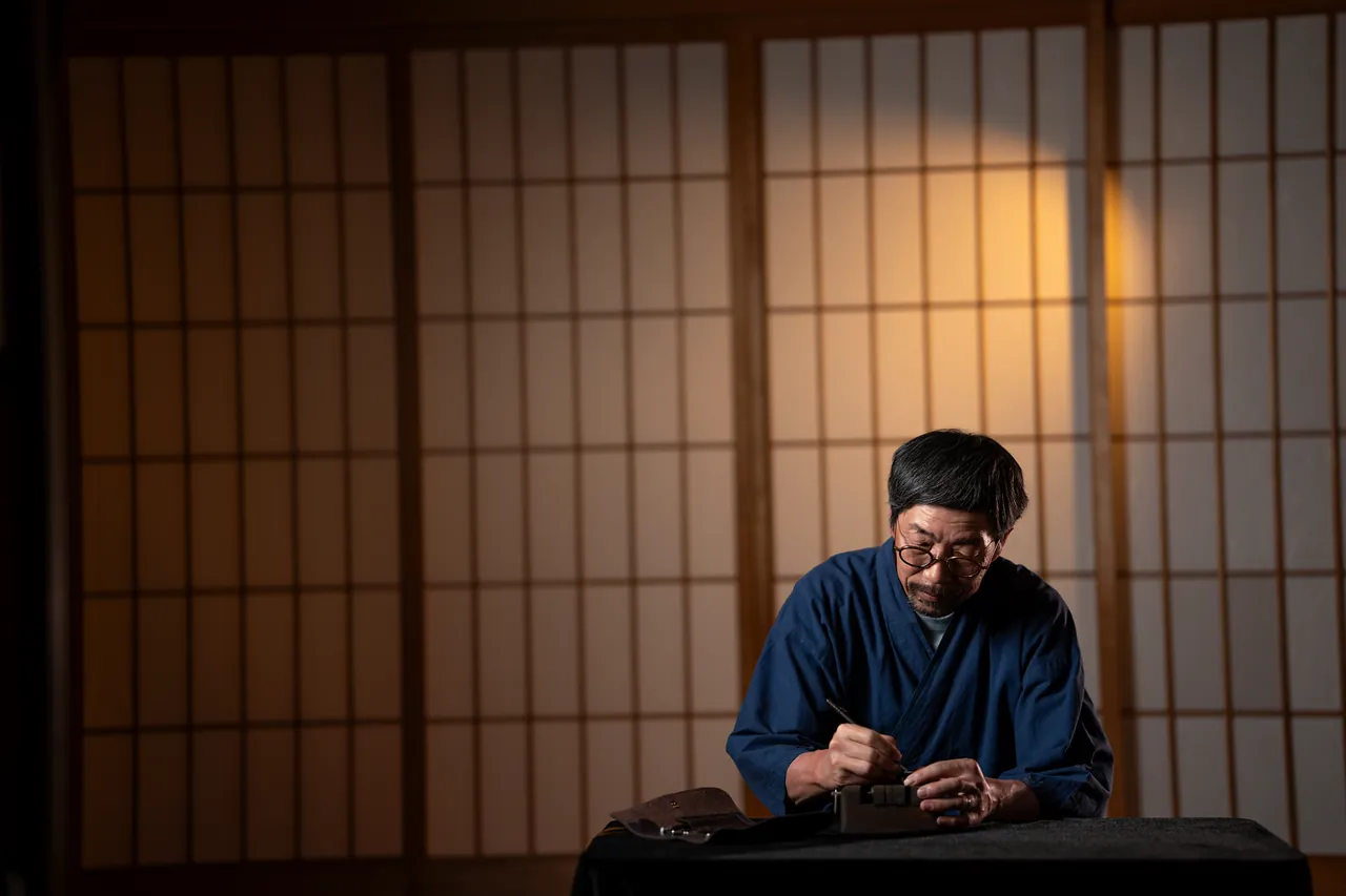 Our craftsman carving a hanko by hand at a low table in front of lit shoji screens